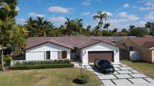 Metal roof on home with palm tree back drop and car on garage driveway 