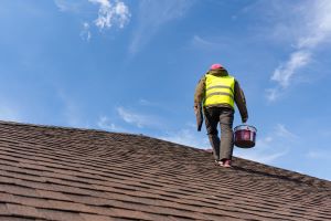 A picture of a roofing technician inspecting a shingle roof