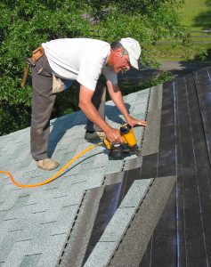 A roofer installing shingles on a home