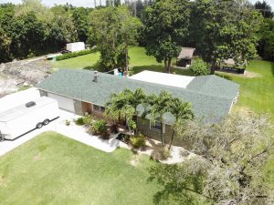 Aerial view of modest home with asphalt shingle roof